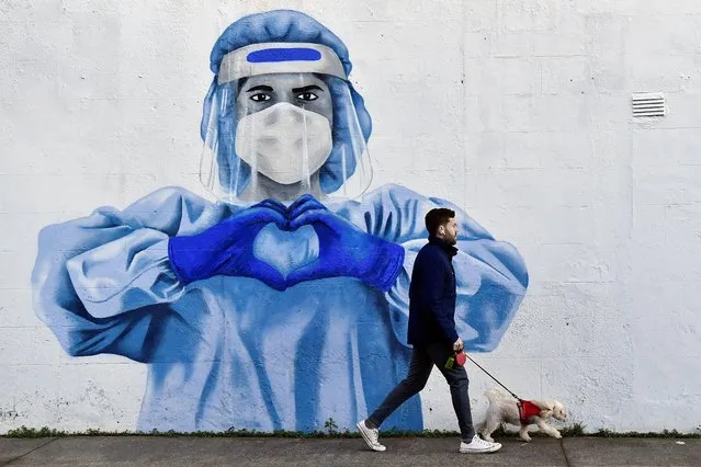 A man walks his dog past a mural depicting a frontline worker amid the spread of the coronavirus disease (COVID-19) in Dublin, Ireland, January 12, 2022. (Photo by Clodagh Kilcoyne/Reuters)