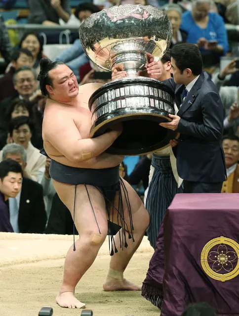 Japanese “yokozuna” or sumo grand champion Kisenosato (L) receives the championship trophy during the awards ceremony following his victory in the Spring Grand Sumo Tournament in Osaka on March 26, 2017. Kisenosato beat ozeki- ranked wrestler Terunofuji in a play- off after both finished the 15- day tournament with matching 13-2 records to take home the trophy. (Photo by AFP Photo/JIJI Press)