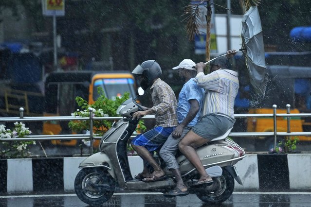 A man riding pillion tries to hold on to an umbrella as it turns inside out in the wind during a rainfall in Chennai, India, Wednesday, June 5, 2024. India receives its monsoon rains from June to October. (Photo by Mahesh Kumar A./AP Photo)