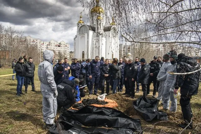 French forensics investigators, who arrived to Ukraine for the investigation of war crimes amid Russia's invasion, stand next to a mass grave in the town of Bucha, in Kyiv region, Ukraine, Tuesday, April 12, 2022. (Photo by Wladyslaw Musiienko/AP Photo)