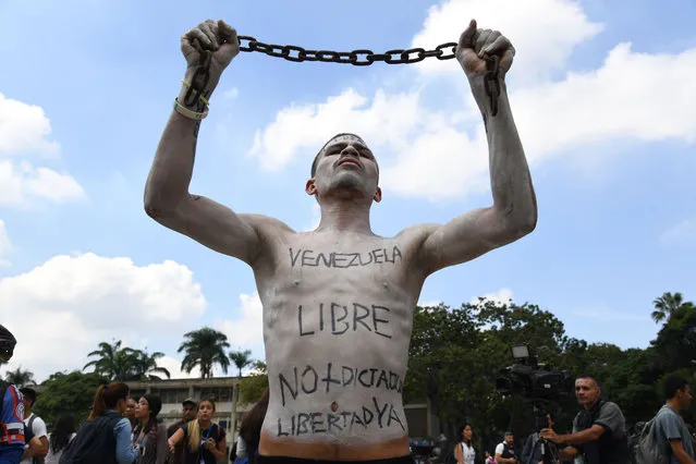 A university student holds a chain with his body painted during a protest against Venezuela's President Nicolas Maduro in Caracas on November 21, 2019. (Photo by Yuri Cortez/AFP Photo)