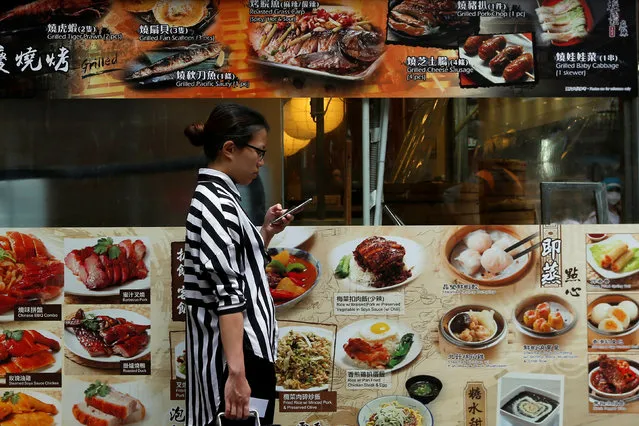 A woman checks her smartphone outside a restaurant at Tsim Sha Tsui shopping district in Hong Kong, China, May 31, 2016. (Photo by Bobby Yip/Reuters)