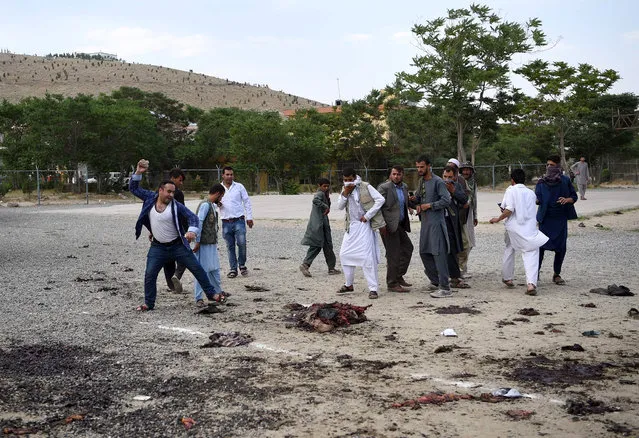 An angry Afghan man (L) throws a rock at what was thought to be the remains of one of the attackers at the site of a series of explosions that targeted a funeral of a politician's son, who was killed during an anti-government protest a day earlier, in Kabul on June 3, 2017. Witnesses reported three blasts at the burial site of Salim Ezadyar, who was among four people killed on June 2 when the protest degenerated into street clashes with police, fuelling anger against the government. (Photo by Wakil Kohsar/AFP Photo)