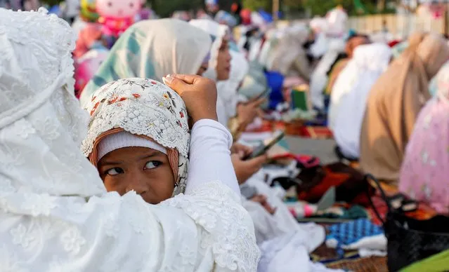 Muslim girl looks on as she attends mass prayers at the Sunda Kelapa port during Eid al-Fitr, marking the end of the holy fasting month of Ramadan, in Jakarta, Indonesia, May 2, 2022. (Photo by Willy Kurniawan/Reuters)