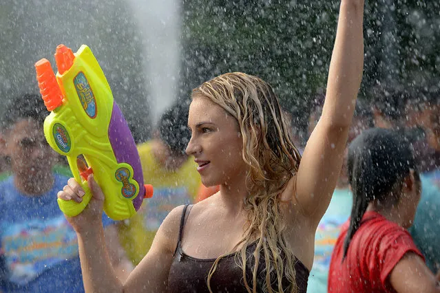 A woman is sprayed with water while holding a water pistol as residents celebrate the feast day of St. John the Baptist in Manila on June 24, 2014. Residents traditionally greet everyone with splashing water in a belief that it is a way of spreading good blessings on St. John's Day. (Photo by Jay Directo/AFP Photo)