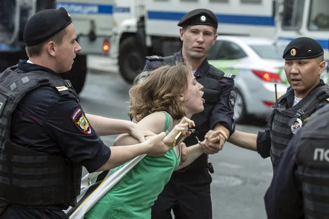 Police officers detain a woman during a march in Moscow, Russia, Wednesday, June 12, 2019. Police and hundreds of demonstrators are facing off in central Moscow at an unauthorized march against police abuse in the wake of the high-profile detention of a Russian journalist. More than 20 demonstrators have been detained, according to monitoring group. (Photo by Pavel Golovkin/AP Photo)