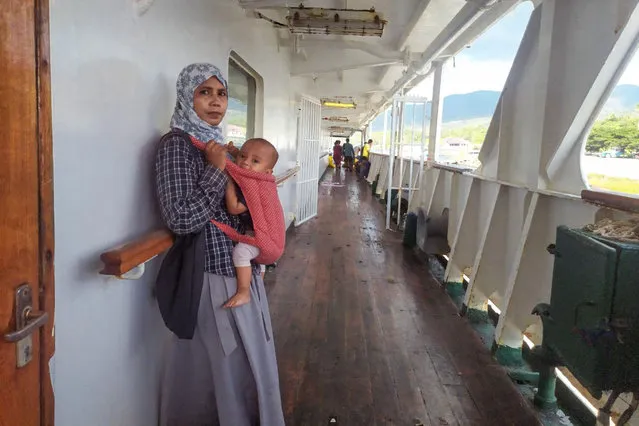 A passenger and her baby stand onboard of the KM Sirimau ferry that was towed to port in Lembata on May 19, 2022. The KM Sirimau has been marooned for two days with 784 passengers and 55 crew members on board after it ran aground along a 184-kilometre (114-mile) route in East Nusa Tenggara province. (Photo by Atagoran/AFP Photo)