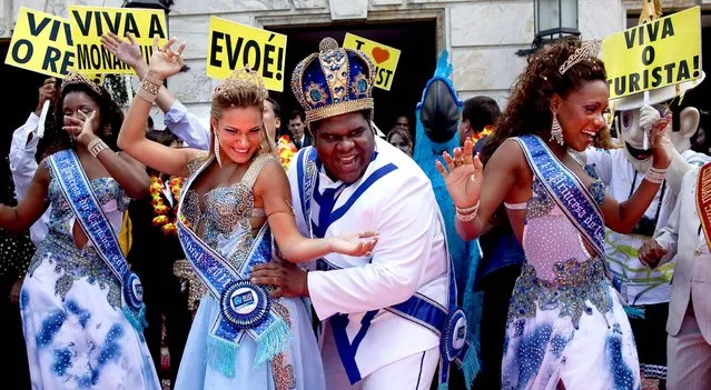 King Momo, the crowned and costumed Milton Rodrigues, flanked by the Carnival queen and two princesses, pose for pictures during carnival celebrations in Rio de Janeiro, Brazil