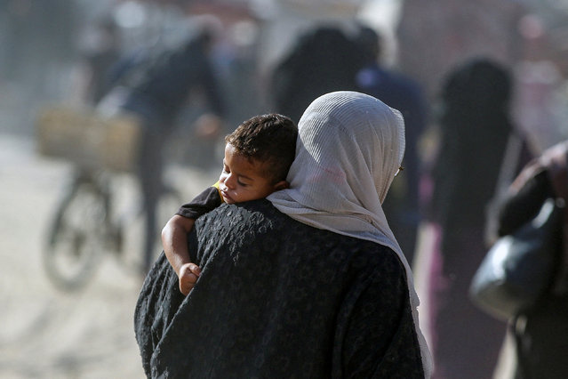 A displaced Palestinian woman carries a child as she makes her way to flee areas in the eastern part of Khan Younis following an Israeli evacuation order, amid the ongoing conflict between Israel and Hamas, in Khan Younis in the southern Gaza Strip on October 7, 2024. (Photo by Hatem Khaled/Reuters)