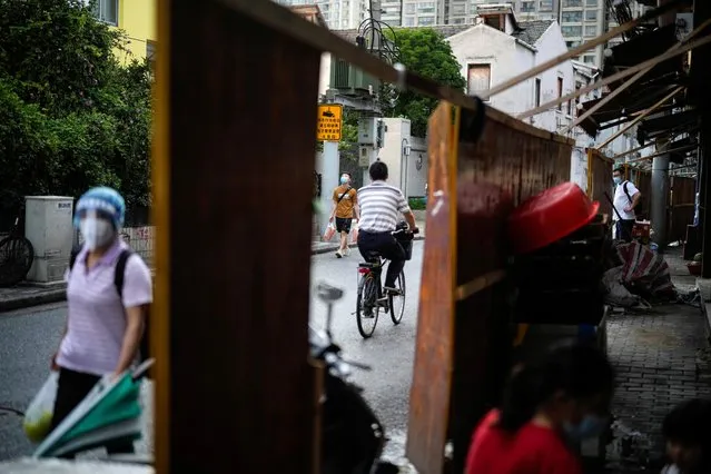 People are pictured at both sides of a barrier of a residential area, amid new lockdown measures in parts of the city to curb the coronavirus disease (COVID-19) outbreak in Shanghai, China on June 24, 2022. (Photo by Aly Song/Reuters)