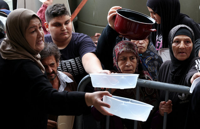 Displaced people queue for food cooked by a charity kitchen, amid ongoing hostilities between Hezbollah and Israeli forces, in downtown Beirut, Lebanon on October 10, 2024. (Photo by Mohamed Azakir/Reuters)