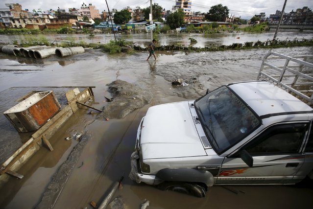 A man walks near a vehicle partially submerged by floodwaters flowing from the swollen Bagmati River caused by heavy rainfall in Kathmandu, Nepal August 17, 2015. (Photo by Navesh Chitrakar/Reuters)