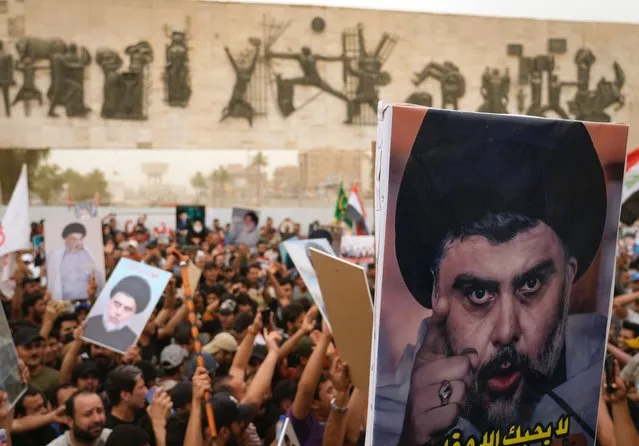 Followers of Shiite cleric Muqtada al-Sadr hold posters with his photo as they celebrate the passing of a law criminalizing the normalization of ties with Israel, in Tahrir Square, Baghdad, Iraq, Thursday, May 26, 2022. (Photo by Hadi Mizban/AP Photo)