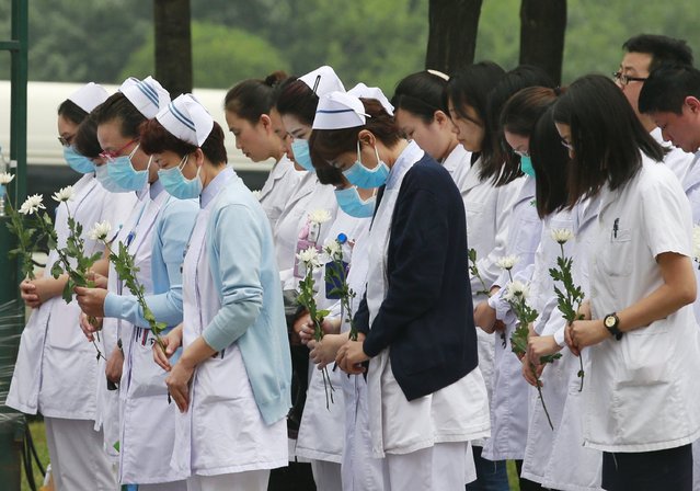 Hospital workers hold a moment of silence at a commemoration ceremony for the victims of last week's massive explosions at Binhai new district in Tianjin, China, August 18, 2015. (Photo by Kim Kyung-Hoon/Reuters)