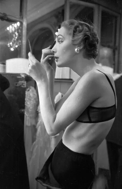1953:  Backstage, a  British model makes some running repairs to her make-up during a fashion show by John Cavanagh