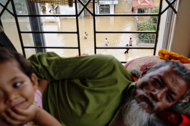 People wading through flood water are seen from a makeshift shelter for affected people, amid severe flooding in the Fazilpur area of Feni, Bangladesh on August 26, 2024. (Photo by Mohammad Ponir Hossain/Reuters)