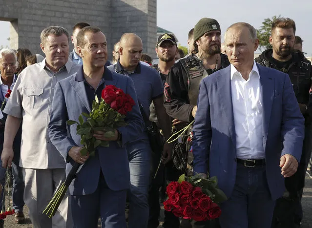 Russian President Vladimir Putin, right, and Russian Prime Minister Dmitry Medvedev, second left, attend a laying ceremony at the memorial of defenders of Sevastopol “35th coastal battery” in Sevastopol, Crimea, Friday, August 18, 2017. Russian biker group leader of Nochniye Volki (the Night Wolves), Alexander Zaldostanov, also known as Khirurg (the Surgeon) is the third from the right. (Photo by Dmitry Astakhov, Sputnik, Government Pool Photo via AP Photo)