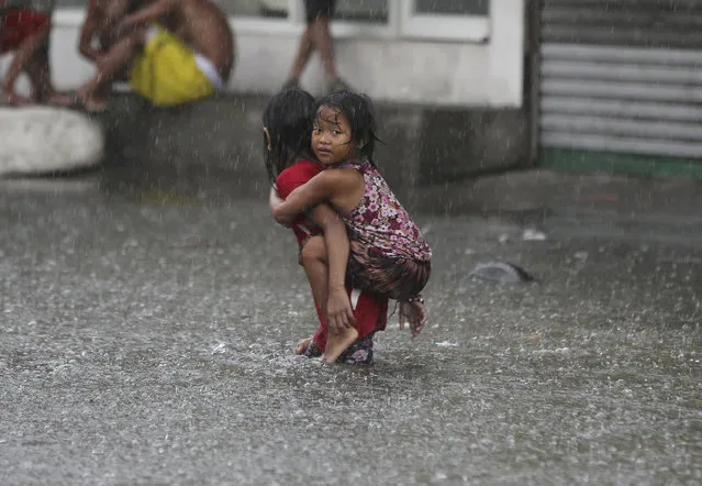 A Filipino girl is carried along a flooded road in suburban Mandaluyong, east of Manila, Philippines, as monsoon downpours intensify while Typhoon Nepartak exits the country on Friday, July 8, 2016. In the Philippine capital, Manila, and outlying provinces, classes in many schools were suspended and at least six flights, including one scheduled to come from Taiwan, were canceled because of stormy weather and floods following monsoon downpours intensified by the typhoon, Filipino officials said. (Photo by Aaron Favila/AP Photo)