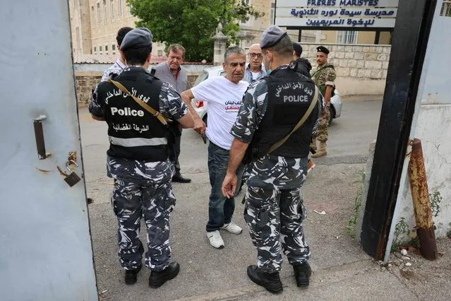 Lebanese policemen check the ID of voters outside a polling station near the Lebanese coastal city of Byblos (Jbeil), north of the capital Beirut, on May 15, 2022, ahead of casting their vote in the parliamentary election. Lebanon voted in its first election since multiple crises dragged it to the brink of failed statehood, with the ruling elite expected to comfortably weather public anger. The parliamentary election is a first test for opposition movements spawned by an unprecedented anti-establishment uprising in 2019 that briefly raised hopes of regime change in Lebanon. (Photo by Joseph Eid/AFP Photo)