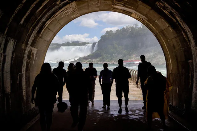 People make their way through the tunnel after a ceremony ahead of the opening of the century-old Tunnel as a new tourist attraction at at the Niagara Parks Power Station in Niagara Falls, Ontario, Canada on June 28, 2022. (Photo by Carlos Osorio/Reuters)