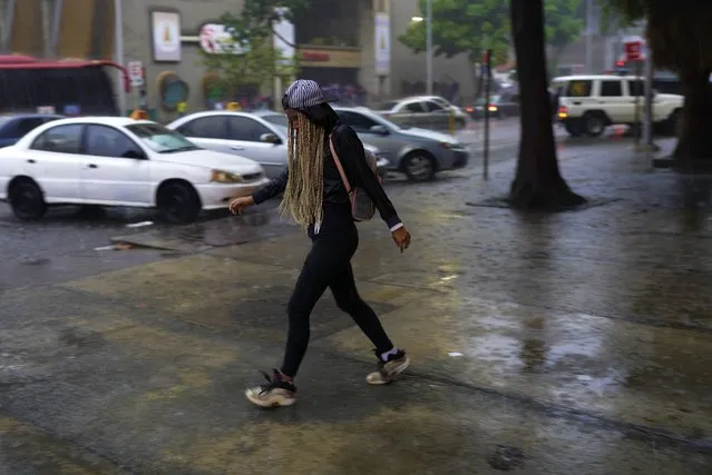 A woman walks under the rain in Caracas, Venezuela, Wednesday, June 29, 2022. As the latest tropical disturbance advances through the area, Venezuela shuttered schools, opened shelters and restricted air and water transportation on Wednesday as President Nicolas Maduro noted that the South American country already has been struggling with recent heavy rains. (Photo by Ariana Cubillos/AP Photo)