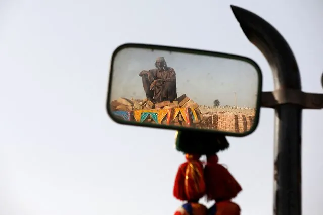 Chaneser, 45, is reflected in a mirror of a tractor trolly, as he takes a break from work, during a heatwave, at a brick kiln factory in Jacobabad, Pakistan, May 14, 2022. (Photo by Akhtar Soomro/Reuters)