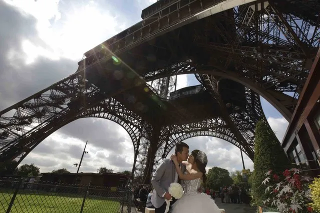 A Chinese couple poses during a pre-wedding photoshoot in front of the Eiffel tower in Paris, France, August 28, 2015. (Photo by Philippe Wojazer/Reuters)