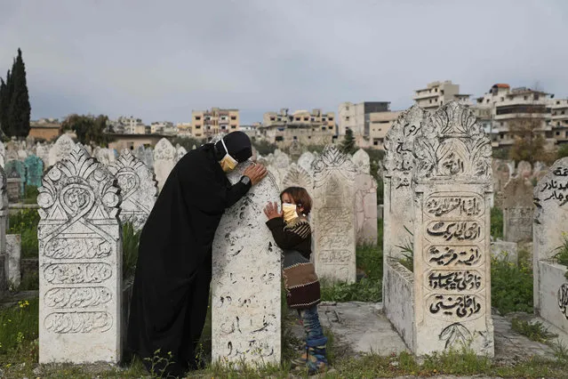 A displaced Syrian woman and her daughter visits a grave of a relative in the town of Ariha in the northern countryside of Syria's Idlib province on April 5, 2020. (Photo by Aaref Watad/AFP Photo)