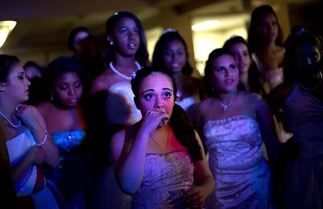 The girls listen to a police officer speak about them during their group debutante ball. It is hoped that the ball will build goodwill between the pacified favelas' residents and the officers who patrol them. (Photo by Silvia Izquierdo/AP Photo via The Palm Beach Post)