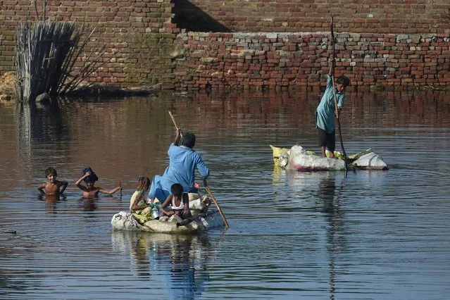 People use rafts to cross a flooded area after monsoon rains on the outskirts of Sukkur, Sindh province, on September 1, 2022. Monsoon rains have submerged a third of Pakistan, claiming at least 1,190 lives since June and unleashing powerful floods that have washed away swathes of vital crops and damaged or destroyed more than a million homes. (Photo by Asif Hassan/AFP Photo)