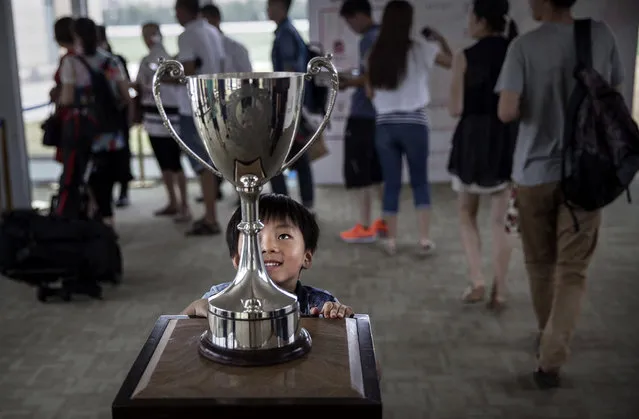 A Chinese boy looks at the cup before tournament play  at the Tianjin Goldin Metropolitan Polo Club on July 17, 2016 in Tianjin, China. China's rising affluence has nurtured growing interest in polo and other past-times regarded as noble or prestigious by the country's elite.  Clubs and international-size polo fields have been built in various cities including Beijing and Shanghai, and on the outskirts of Tianjin, where membership at the exclusive Goldin Metropolitan, China's largest polo club, is by invitation-only and fees can be significant for polo team owners. Increasingly, wealthy Chinese parents are choosing polo and other equestrian activities for their children as a way to bolster their credentials for admission to top-tier universities in the United States and the United Kingdom. (Photo by Kevin Frayer/Getty Images)