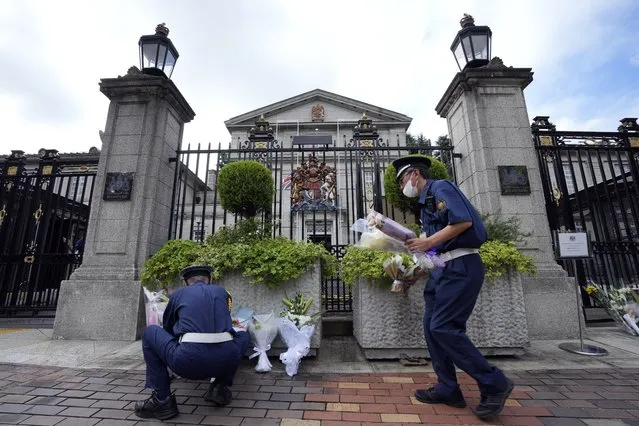 Security guards move condolence flowers to another position outside the British Embassy following the death of Queen Elizabeth II, Friday, September 9, 2022, in Tokyo. (Photo by Eugene Hoshiko/AP Photo)