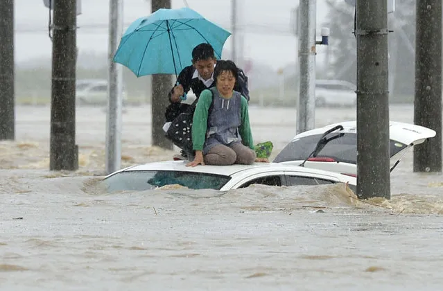 People wait for help as the vehicles are submerged in flooding in Joso, Ibaraki prefecture, northeast of Tokyo Thursday, September 10, 2015. (Photo by Kyodo News via AP Photo)