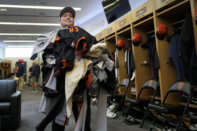 San Francisco Giants clubhouse attendant Riley Halpin gathers a mound of dirty clothes in the clubhouse after spring training baseball practice at the team's facility, Monday, February 17, 2025, in Scottsdale, Ariz. (Photo by Carolyn Kaster/AP Photo)