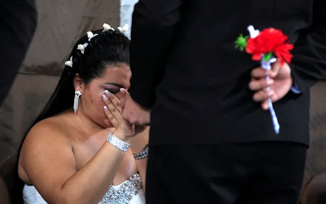 A couple reacts during a mass wedding ceremony, held for 17 male inmates, in the Carcel Villa Hermosa prison in Cali, Colombia, August 19, 2016. (Photo by Jaime Saldarriaga/Reuters)