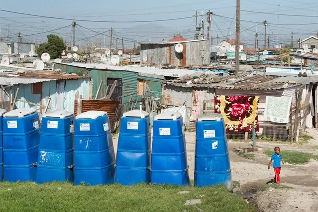 A boy walks past portable toilets at an informal settlement in Khayelitsha, a mostly impoverished township, about 35km from the centre of Cape Town, South Africa on November 10, 2017. (Photo by Rodger Bosch/AFP Photo)