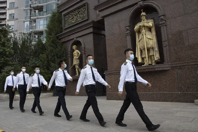Security guards wearing masks to curb the spread of the coronavirus march past a community with European style statues in Beijing on Monday, June 29, 2020. Even as the world surpassed two sobering coronavirus milestones Sunday – 500,000 confirmed deaths, 10 million confirmed cases – and hit another high mark for daily new infections, China on Monday reported a further decline in new confirmed cases. (Photo by Ng Han Guan/AP Photo)