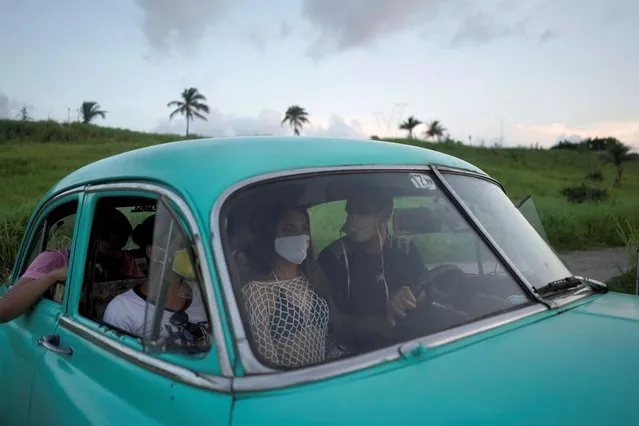 Estefani Linares rides inside a vintage car after a photo session for her quinceanera (coming of age of 15-year-olds) celebration amid coronavirus disease (COVID-19) spread concerns, in Havana, Cuba, July 15, 2020. Photographer Manuel Padron, who has been shooting quinceaneras for more than 10 years, says the girls find sporting a face mask – called “nasobuco” or “nose mouth” in Cuban Spanish – eye-catching “as if it was part of the whole show”. (Photo by Alexandre Meneghini/Reuters)