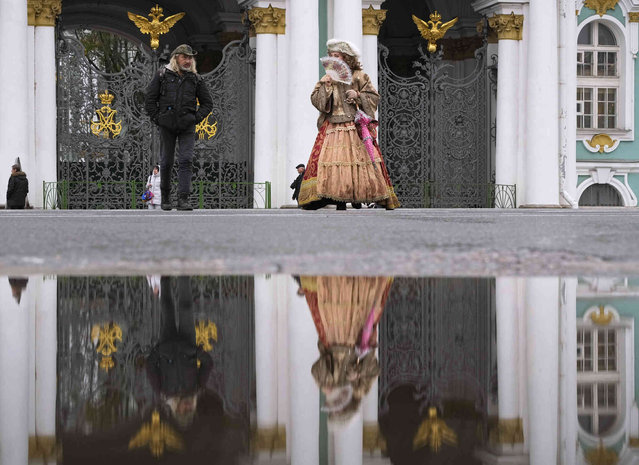A street performer wearing 18th century costume and earning money by posing for photos, walks at the Palace Square in St. Petersburg, Russia, Thursday, November 10, 2022. (Photo by Dmitri Lovetsky/AP Photo)