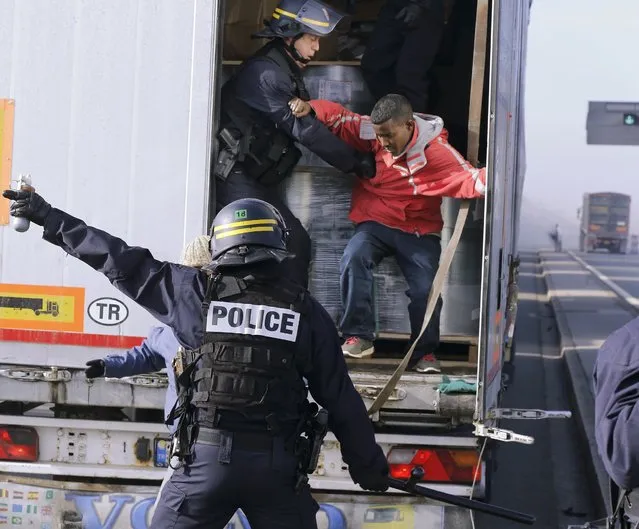 French riot policemen force out migrants who were hidden in a lorry which makes its way to the ferry terminal in Calais October 22, 2014. Britain and France have agreed to improve border controls and cooperate more closely in an effort to control a growing number of illegal immigrants trying to cross the English Channel from the French port city of Calais to Britain. (Photo by Pascal Rossignol/Reuters)