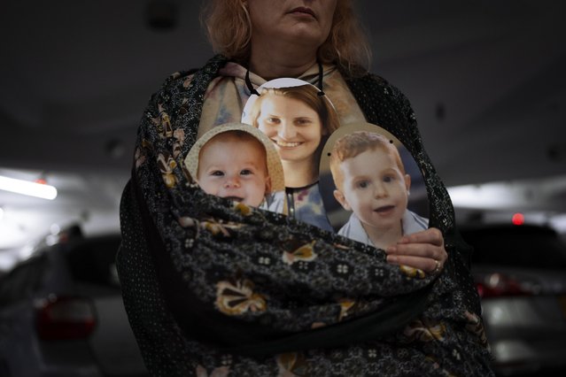 A woman holds a mask depicting the faces of Shiri Bibas and her sons Kfir and Ariel, Israelis who are being held hostage in the Gaza Strip by the Hamas militant group, during a protest demanding the release of the hostages from Hamas captivity, in Tel Aviv, Israel, Wednesday, February 21, 2024. The activists participated in a performance called “Sorry we were kidnapped”, Participants wore masks with the faces of hostages in a desperate plea to return the approximately 100 hostages still held in Gaza. (Photo by Oded Balilty/AP Photo)