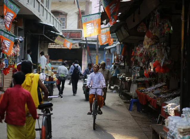 A young Hindu priest rides a bicycle past flags of the Bharatiya Janata Party (BJP) in an alley in Ayodhya in Uttar Pradesh May 6, 2014. (Photo by Anindito Mukherjee/Reuters)