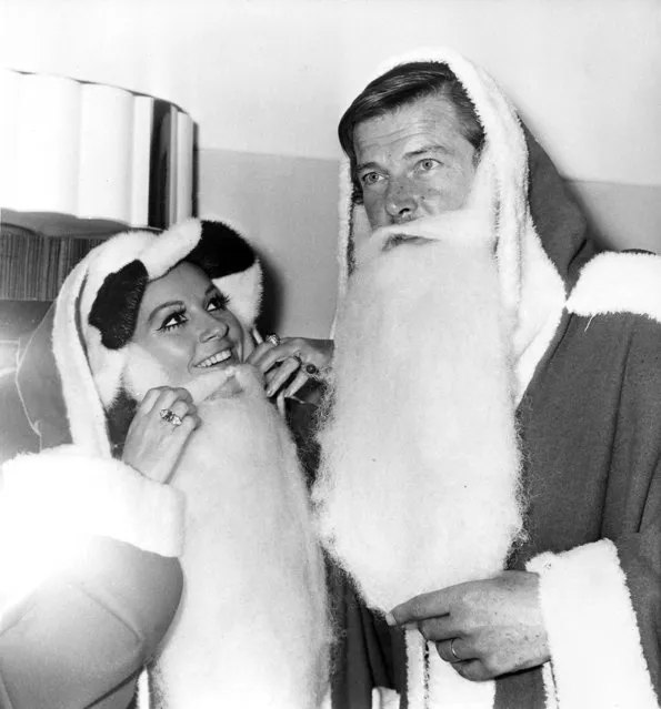 Actors Luisa Mattioli and her husband Roger Moore don “Father Christmas” costumes at the Variety Club of Great Britain's Christmas luncheon at the Savoy Hotel in London, December 9, 1969.  They are collecting gifts for sick and deprived children. (Photo by Bob Dear/AP Photo)