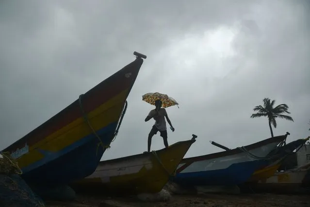 A boy walks over fishing boats on Shore temple beach as Cyclone Mandous is expected to make landfall, in Mahabalipuram, near Chennai, India, 09 December 2022. According to the Indian Meteorological Department (IMD) heavy rainfall is expected across Tamil Nadu, Puducherry and Andhra Pradesh, with a red alert issued for three districts in the state of Tamil Nadu. All educational institutes remain closed in Chennai and several other districts as a precautionary measure. (Photo by Idrees Mohammed/EPA/EFE/Rex Features/Shutterstock)