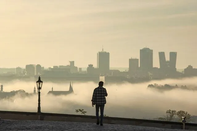 A man walks across the Hradcanska Square in Prague on a foggy morning of October 23, 2022. (Photo by Michal Cizek/AFP Photo)