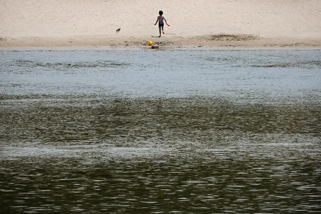 A small child runs on a beach on the banks of the river Danube in Calarasi, southern Romania, Monday, July 27, 2020. Romania is registering more than 1,000 new COVID-19 infections daily, over the past five days, levels that are more than twice as high as the ones during the national lockdown period, and are blamed on people's failure to observe the prevention regulations, like the use of face masks and maintaining social distancing. (Photo by Vadim Ghirda/AP Photo)