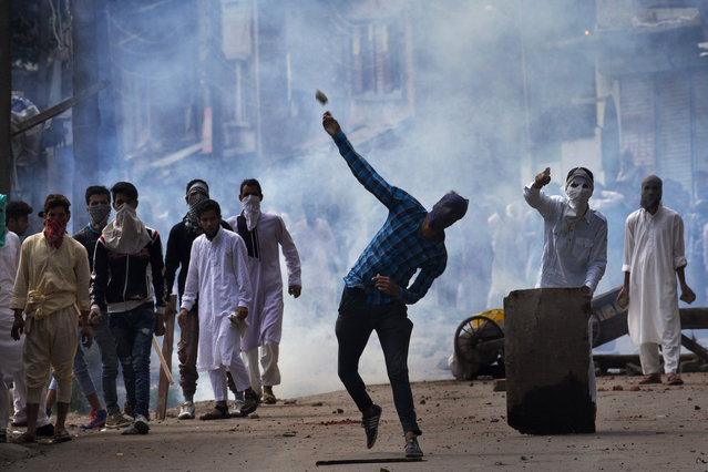 A Kashmiri throws a rock at Indian security personnel during a protest after Eid al-Adha prayers in Srinagar, Indian controlled Kashmir, Tuesday, September 13, 2016. Security forces fired tear gas and shotgun pellets to quell protesters in several places, as a security lockdown marred Eid festivities in the troubled region. Shops and businesses were closed, with a curfew in effect in the entire Kashmir Valley. (Photo by Dar Yasin/AP Photo)