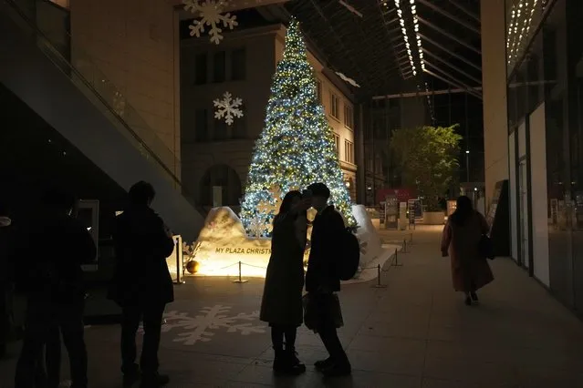 A woman and a man pose for their selfie by a Christmas tree on Christmas Eve in Tokyo, Saturday, December 24, 2022. (Photo by Hiro Komae/AP Photo)