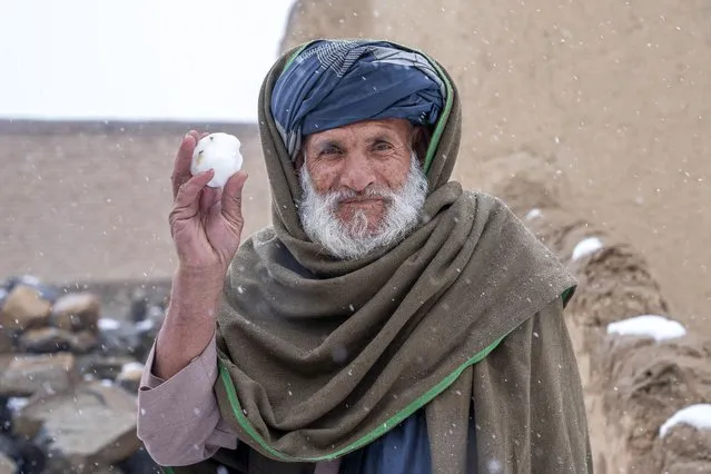 An old Afghan man holds a snowball during snowfall, on the outskirts of Kabul, Afghanistan, Thursday, December 29, 2022. (Photo by Ebrahim Noroozi/AP Photo)