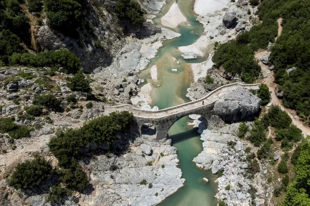 A person walks on the bridge at the Shushica tributary of the Vjosa River, in Brataj, Albania on June 12, 2022. Picture taken with a drone on June 12, 2022. (Photo by Florion Goga/Reuters)